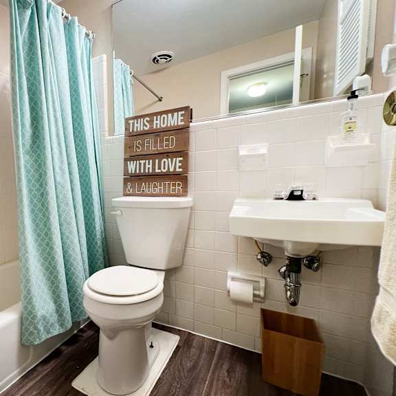 a bathroom with a toilet, sink, and a sign that says "this home is filled with love & laughter.".