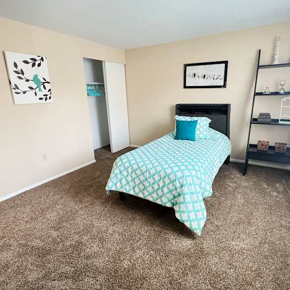 a bedroom with a bed, a shelf, and a picture on the wall.