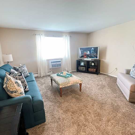 a living room with a dark blue couch, a coffee table, and a television.