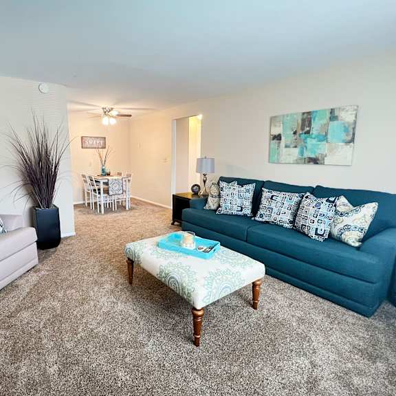 a living room with a grey couch, a blue couch, a wooden coffee table, and a rug.
