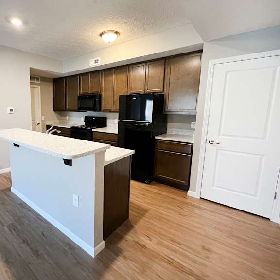 an open kitchen and living room with a white island and black appliances