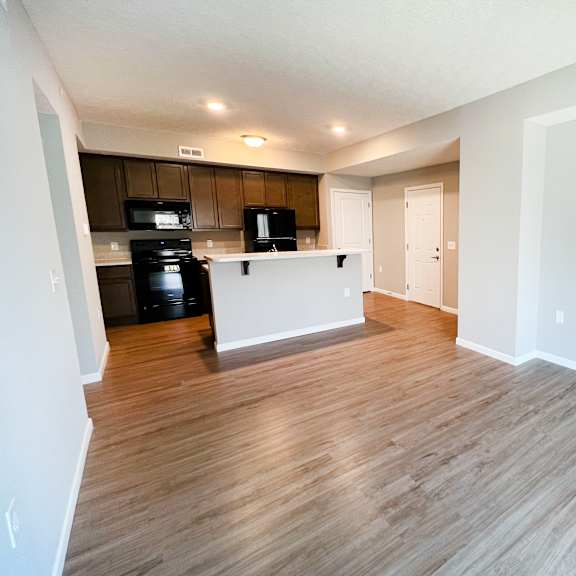 an empty living room and kitchen with wood flooring  at brookfield village apartments, grove city