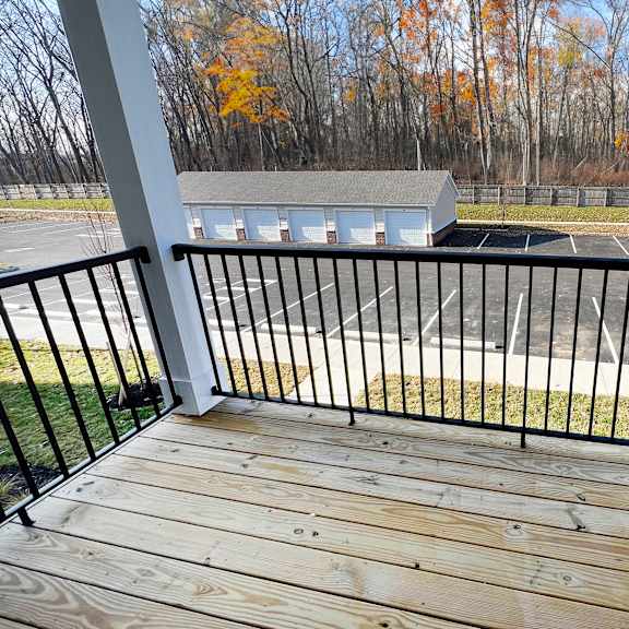 a balcony with a view of a parking lot and trees  at brookfield village apartments, grove city