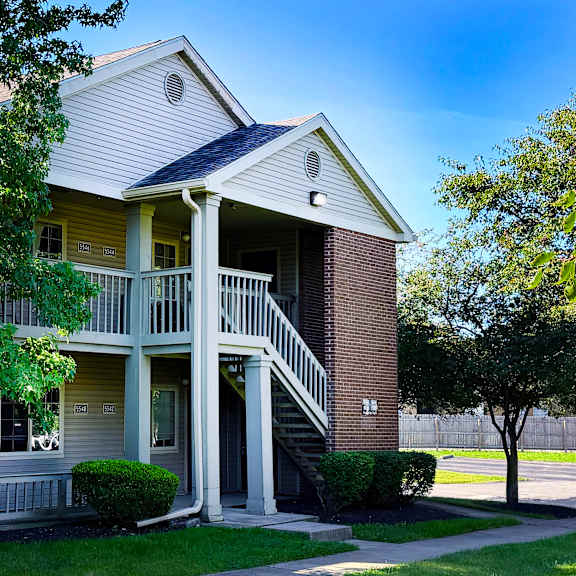 a two-story house with a balcony and a tree in front.