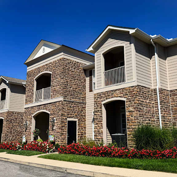 a large building with a balcony and a flower bed in front.