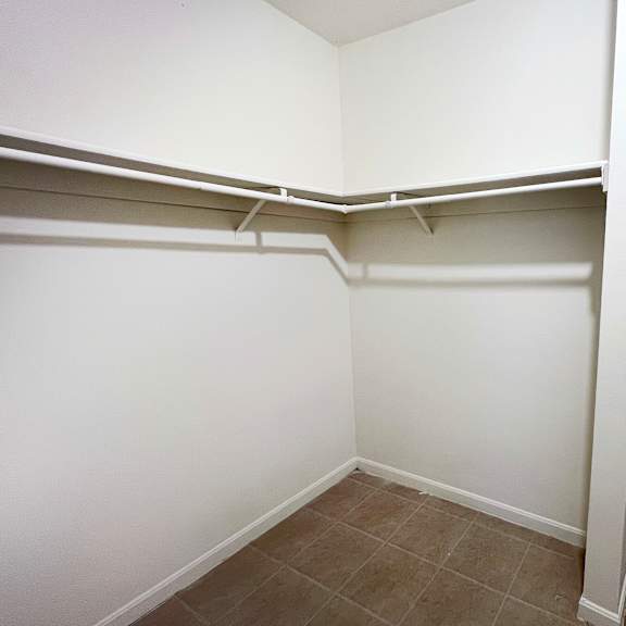 a white closet with shelves and a tiled floor.