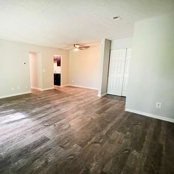 the living room and dining room of an empty home with wood flooring at crown crossing apartments, amelia, ohio 45102