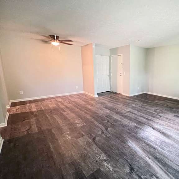 an empty living room with wood floors and a ceiling fan at crown crossing apartments, amelia, oh