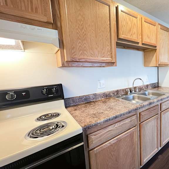a kitchen with wooden cabinets and a white stove top oven at crown crossing apartments, amelia, ohio, 45102