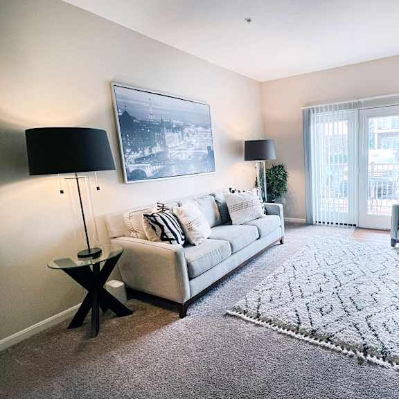 a living room with a grey couch, a black floor lamp, and a large picture on the wall.