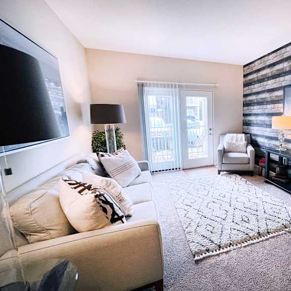 a living room with a couch, a rug, a tv, and a wooden wall.