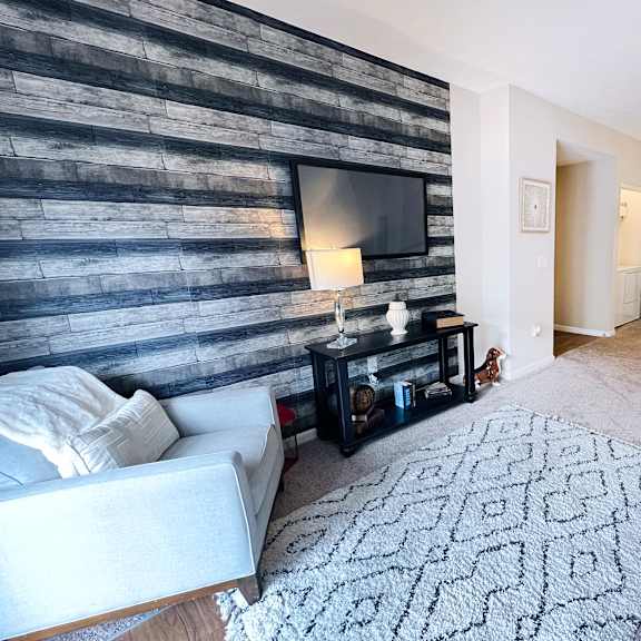 a living room with a white couch and a wooden wall.