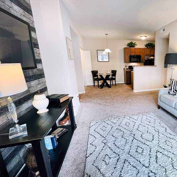 a living room with a grey couch, a patterned rug, and a black and white photo on the wall.