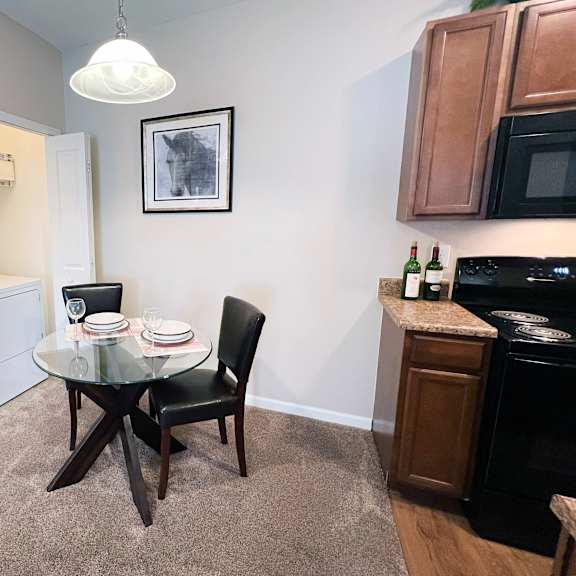 a small dining area with a glass table and a black chair.