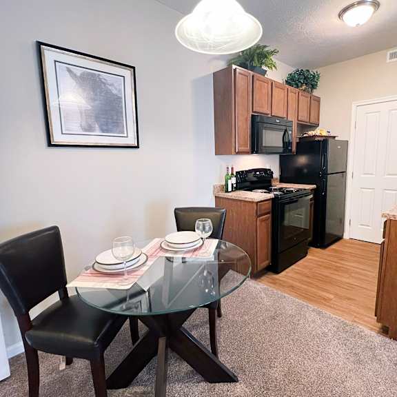 a dining table with a glass top and four chairs around it.