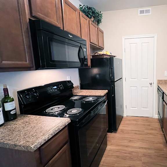 a kitchen with black appliances and brown cabinets.