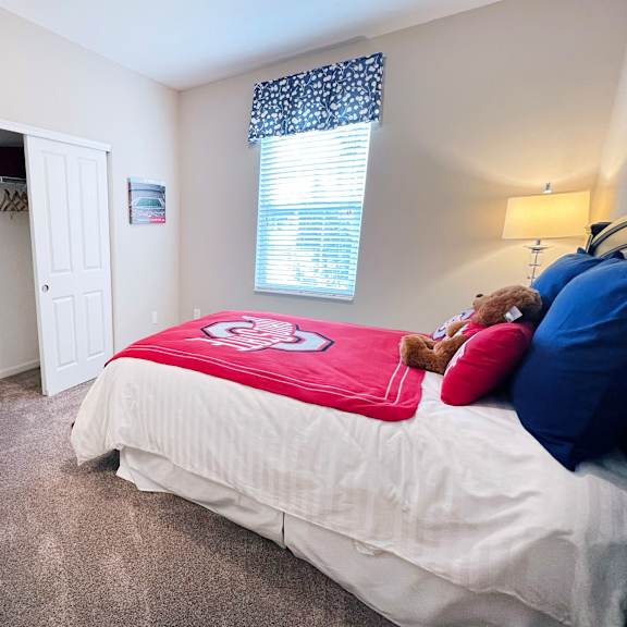a bedroom with a bed, dresser, and a television.