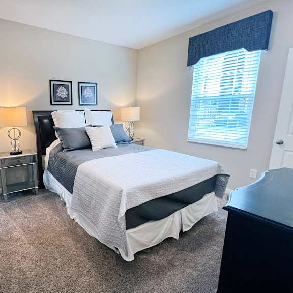 a bedroom with a bed, nightstands, and two wall lamps.