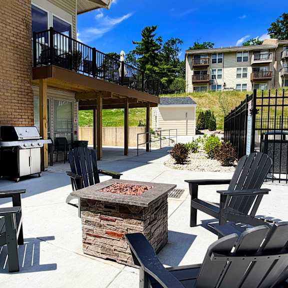 a patio with black chairs and a fire pit.