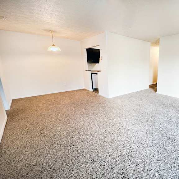 an empty living room with white walls and carpet at four worlds apartments, cincinnati, oh