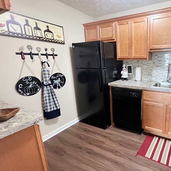 a kitchen with black appliances and wooden cabinets at fox run apartments, cincinnati