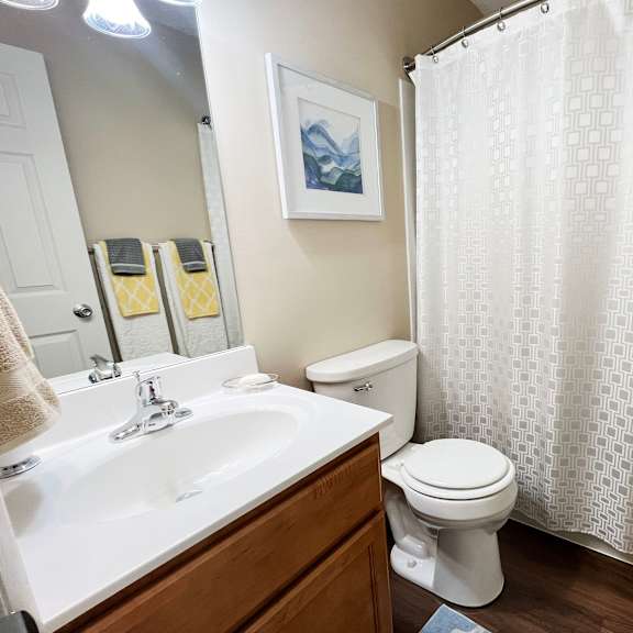 a bathroom with a white shower curtain and a toilet and sink at fox run apartments, cincinnati
