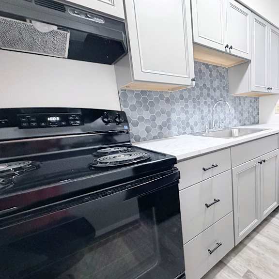 a kitchen with a black stove top oven and white cabinets.