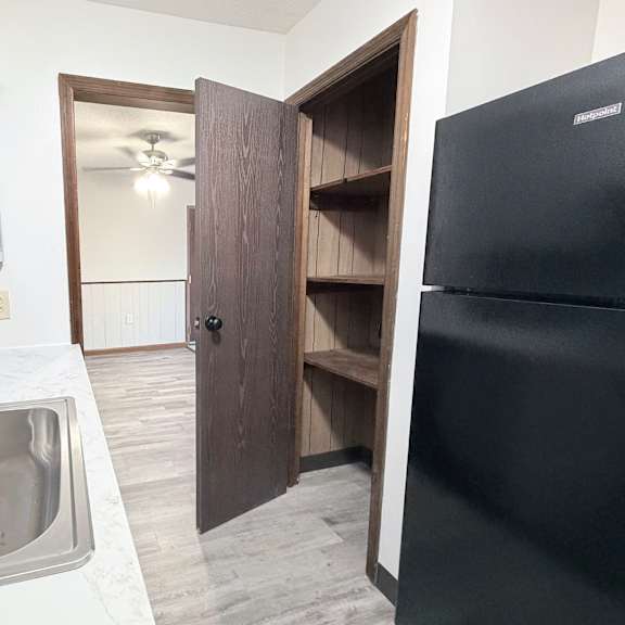 a kitchen with a black refrigerator and a sink with a silver faucet.
