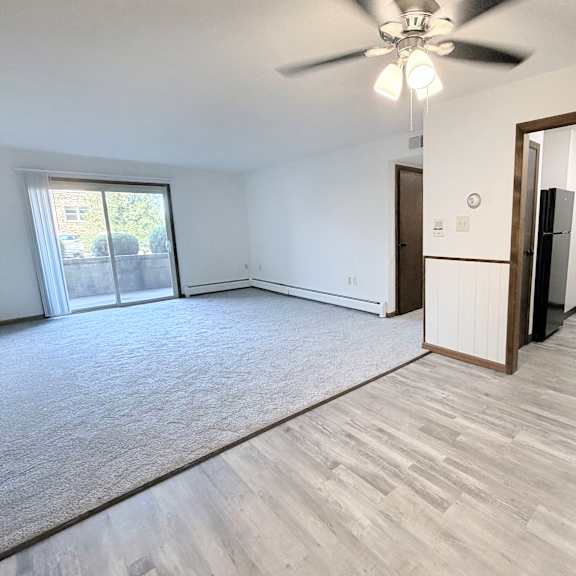 a room with a ceiling fan and a door leading to another room.