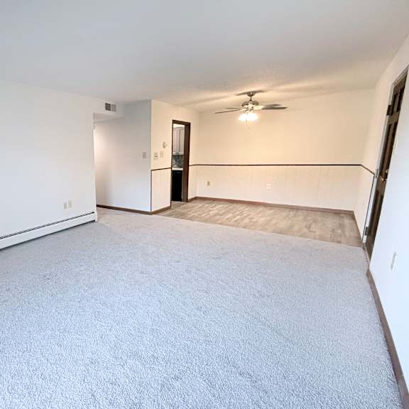 a spacious room with a carpeted floor and a ceiling fan.