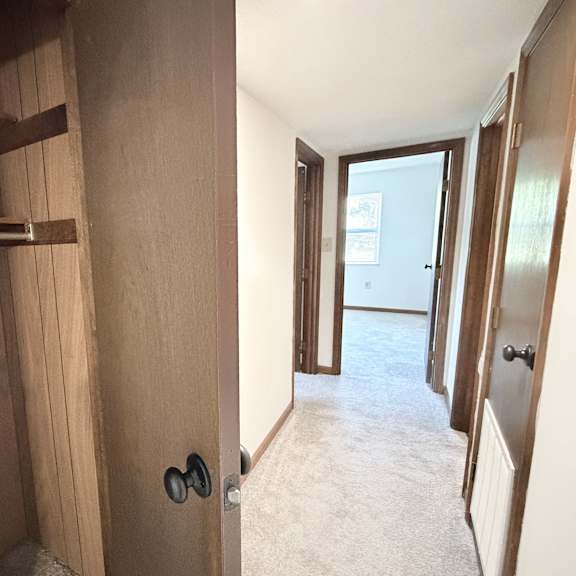 a hallway with a door on the right and a shelf on the left.