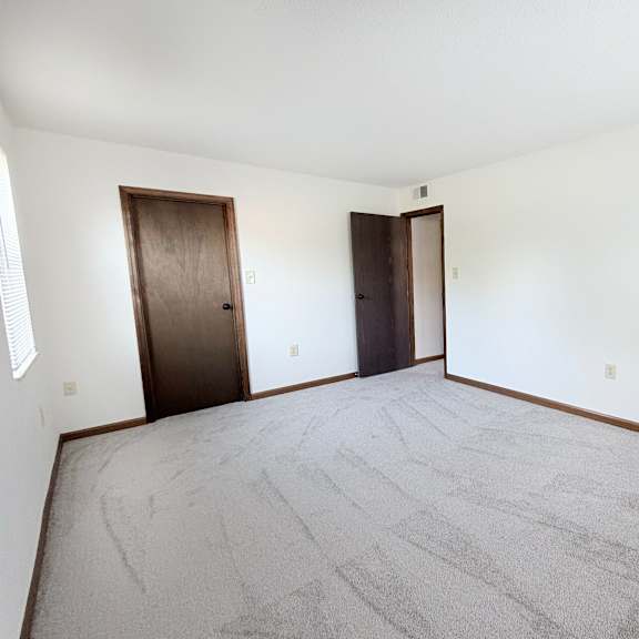 a room with a carpeted floor and two doors.