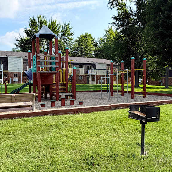 a playground with a slide and a swing set in front of a building.