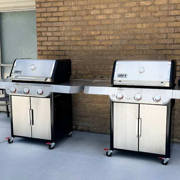 two gas grills are on a patio.