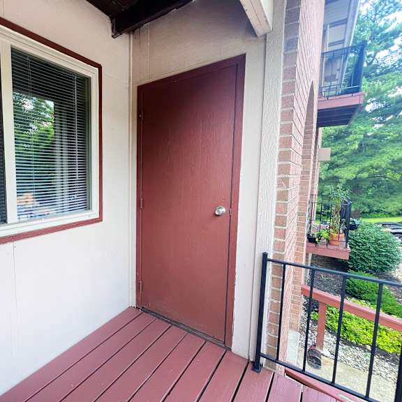 a red door is on the right side of a white wall.