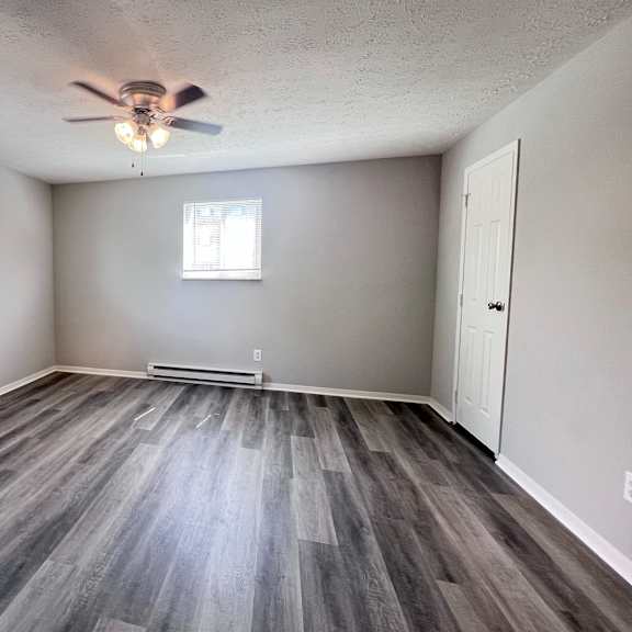 a room with a ceiling fan and wooden flooring.