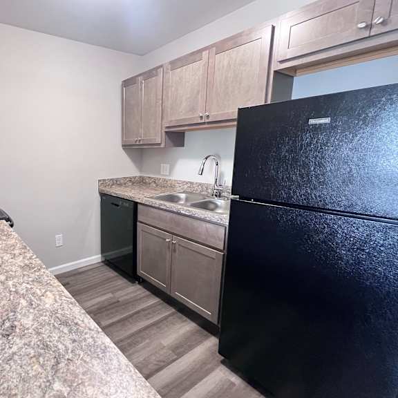 a kitchen with a black refrigerator and granite countertop.