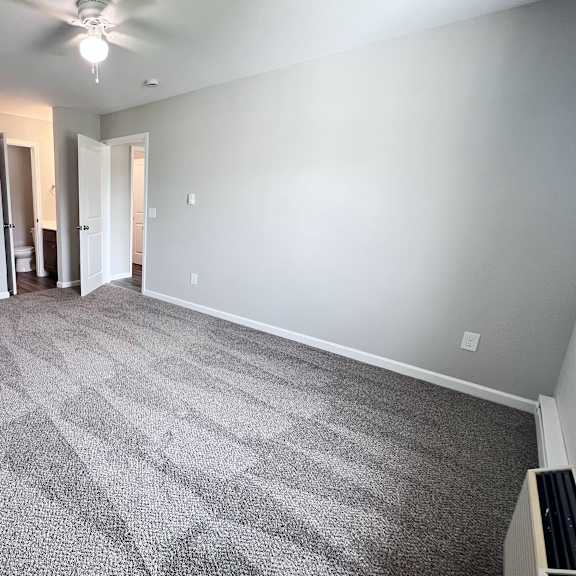 a room with a carpeted floor and a ceiling fan.