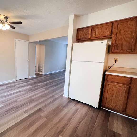 a room with a white refrigerator and wooden floors.