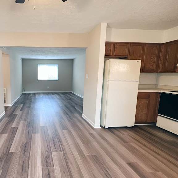 a room with wooden flooring and a white refrigerator.