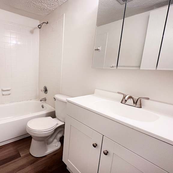 a white bathroom with a toilet, sink, and bathtub.