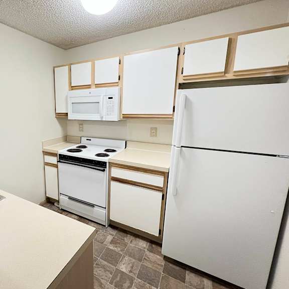 an empty kitchen with white appliances and white cabinets at eagle crest apartments, galloway, oh 43119