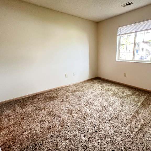 an empty bedroom with carpet and a window at eagle crest apartments, ohio, 43119