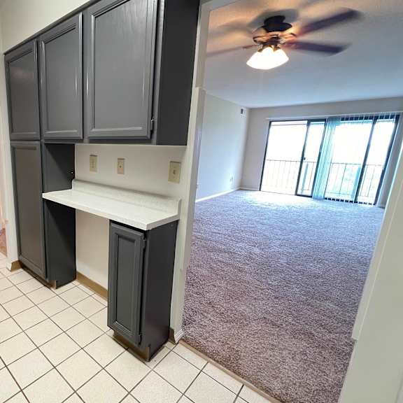 a kitchen with black cabinets and an empty living room with a ceiling fan at indian lookout apartments, cincinnati, 45238
