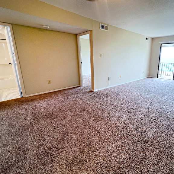 an empty living room with a door to a balcony at indian lookout apartments, cincinnati