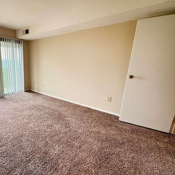 an empty living room with a sliding glass door to a balcony at indian lookout apartments, cincinnati, ohio