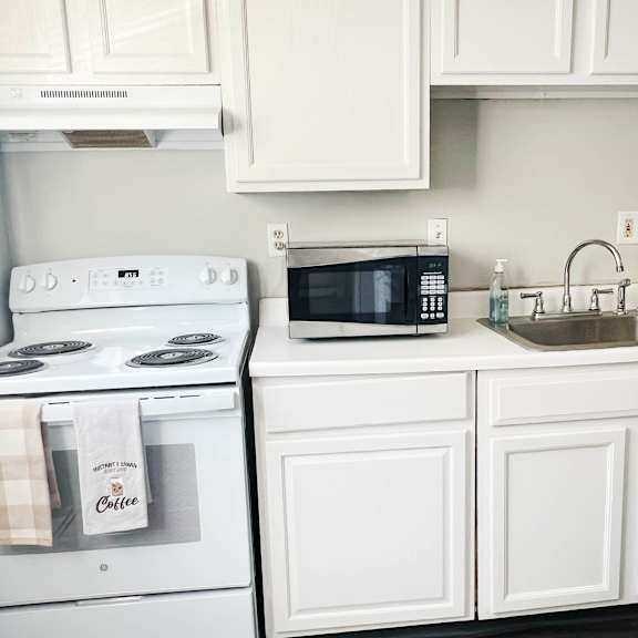 a kitchen with white cabinets and a sink and a stove at crown court apartments, kentucky, 41042