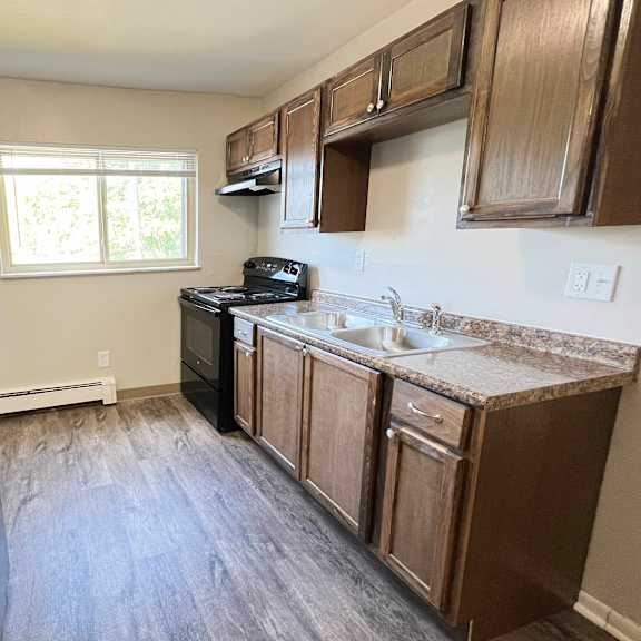 an empty kitchen with wooden cabinets and a black refrigerator at crown court apartments, kentucky, 41042