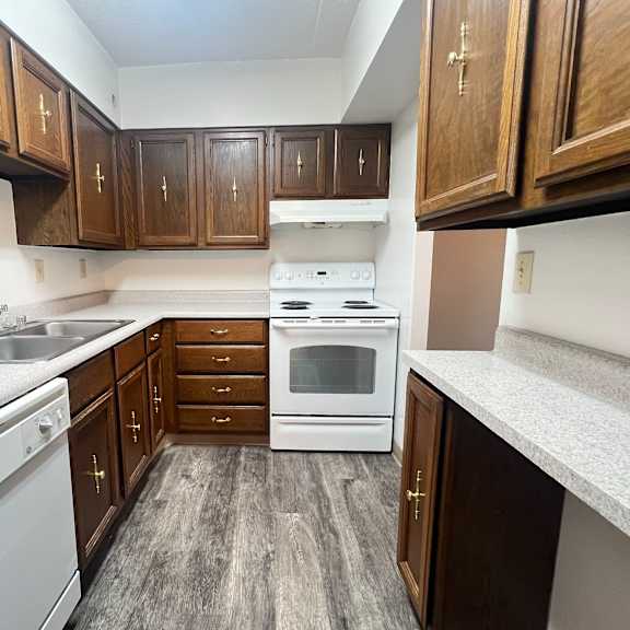 a kitchen with wooden cabinets and a white stove top oven.