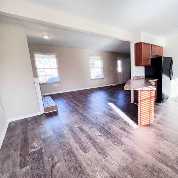 a kitchen area with a black fridge and wooden cabinets.